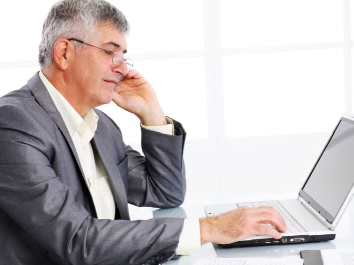 Businessman sitting at his desk researching value propositions on his laptop