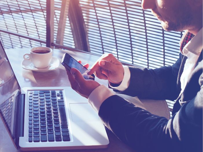 Accountant sitting at table with coffee posting on social media