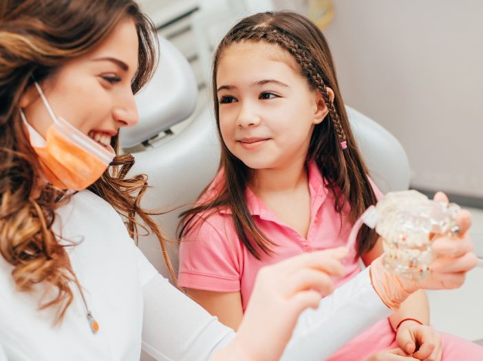 Dentist showing a little girl how to brush her teeth properly