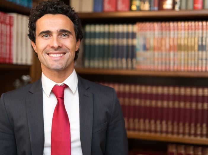 Personal Injury lawyer standing in from law books on shelves