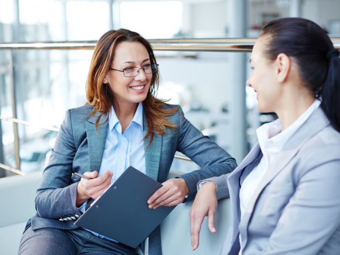 Senior financial consultant with clip board smiling and talking with client