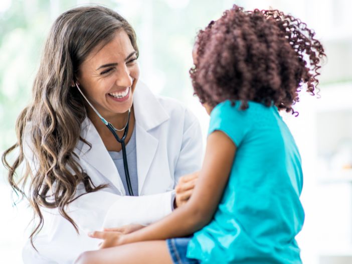 pediatrician examining a little girl smiling