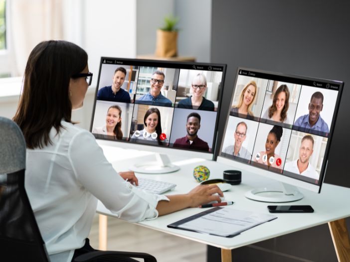 Lady hosting a webinar at desk with two computer screens