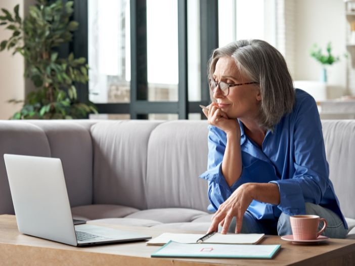 Lady watching a webcast on laptop and taking notes