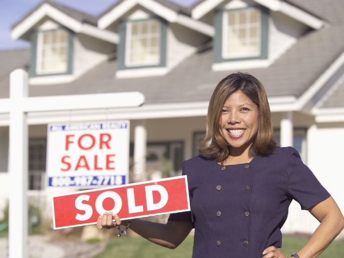 real estate agent holding sold sign from clients she found using email marketing