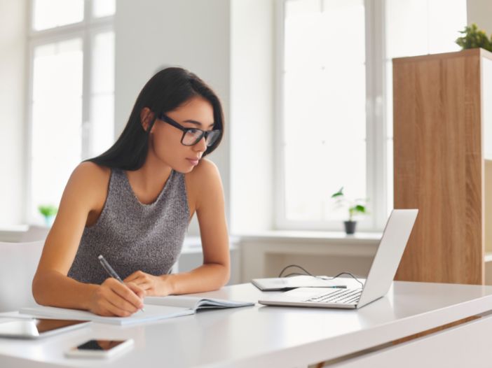 woman watching a company webcast and taking notes